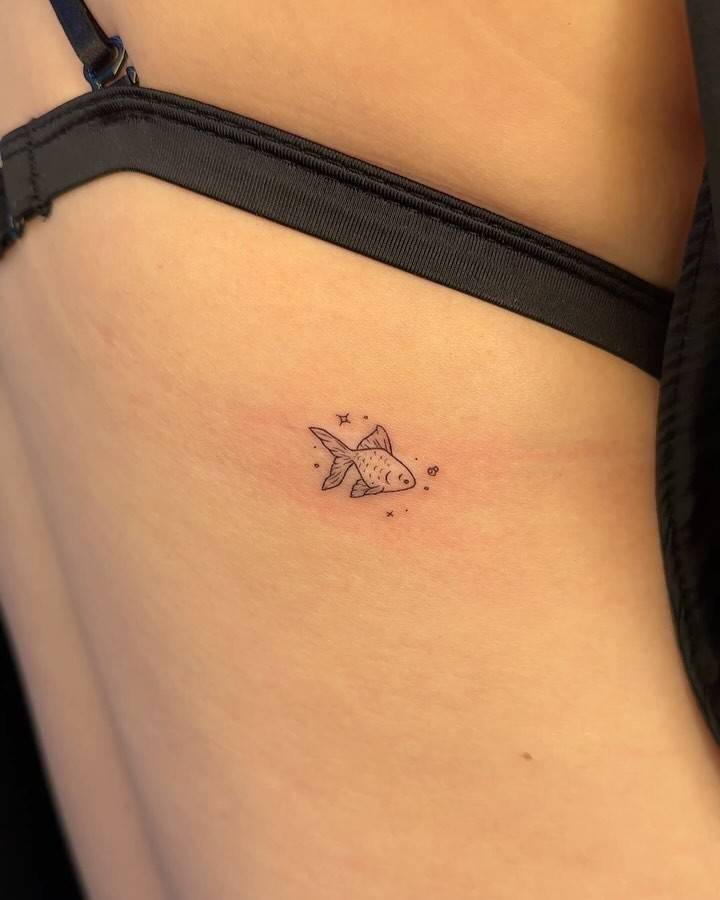 Illustrative style little fish tattoo located on the back.