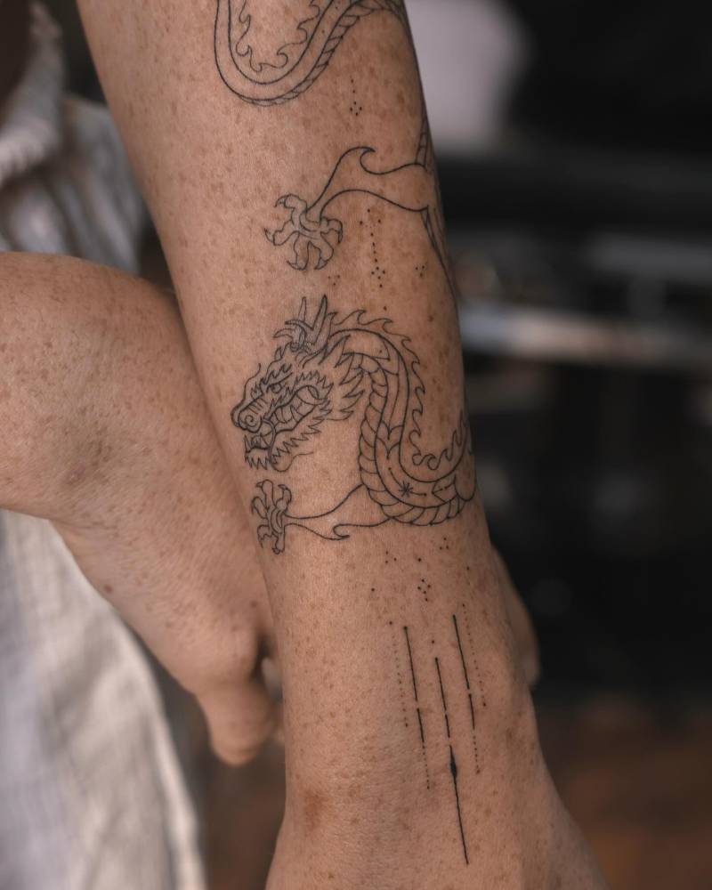 Hand poked dragon tattoo located on the forearm.