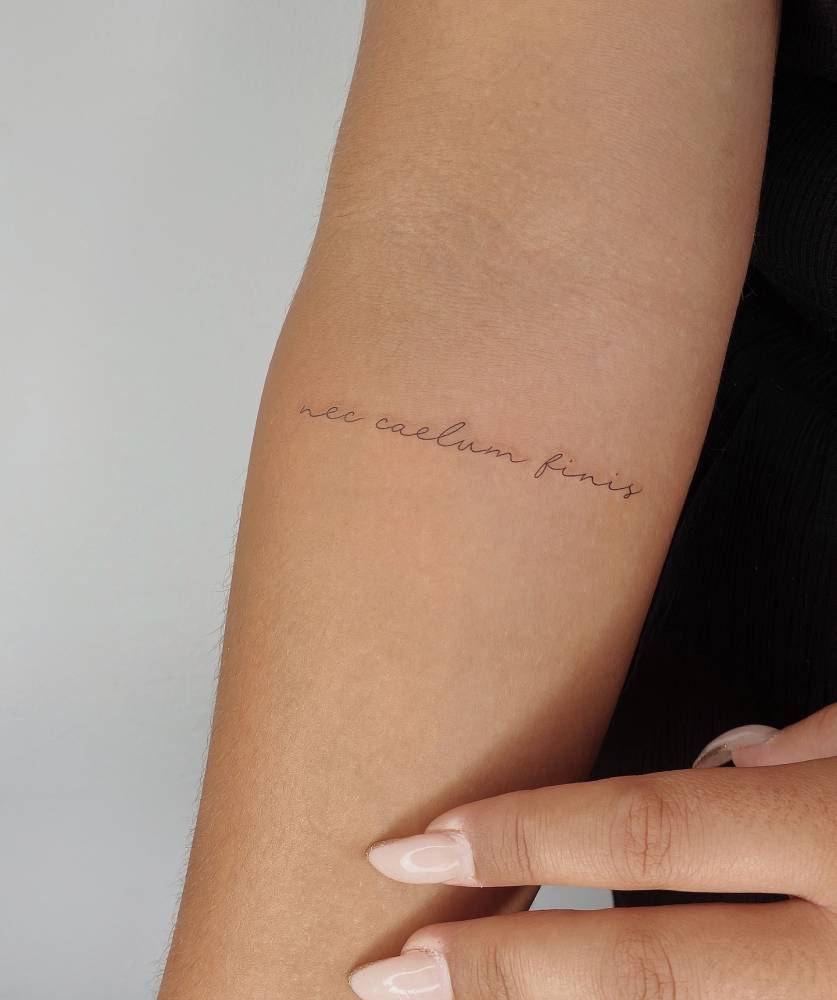 "Nec caelum finis" lettering tattoo located on the inner forearm.