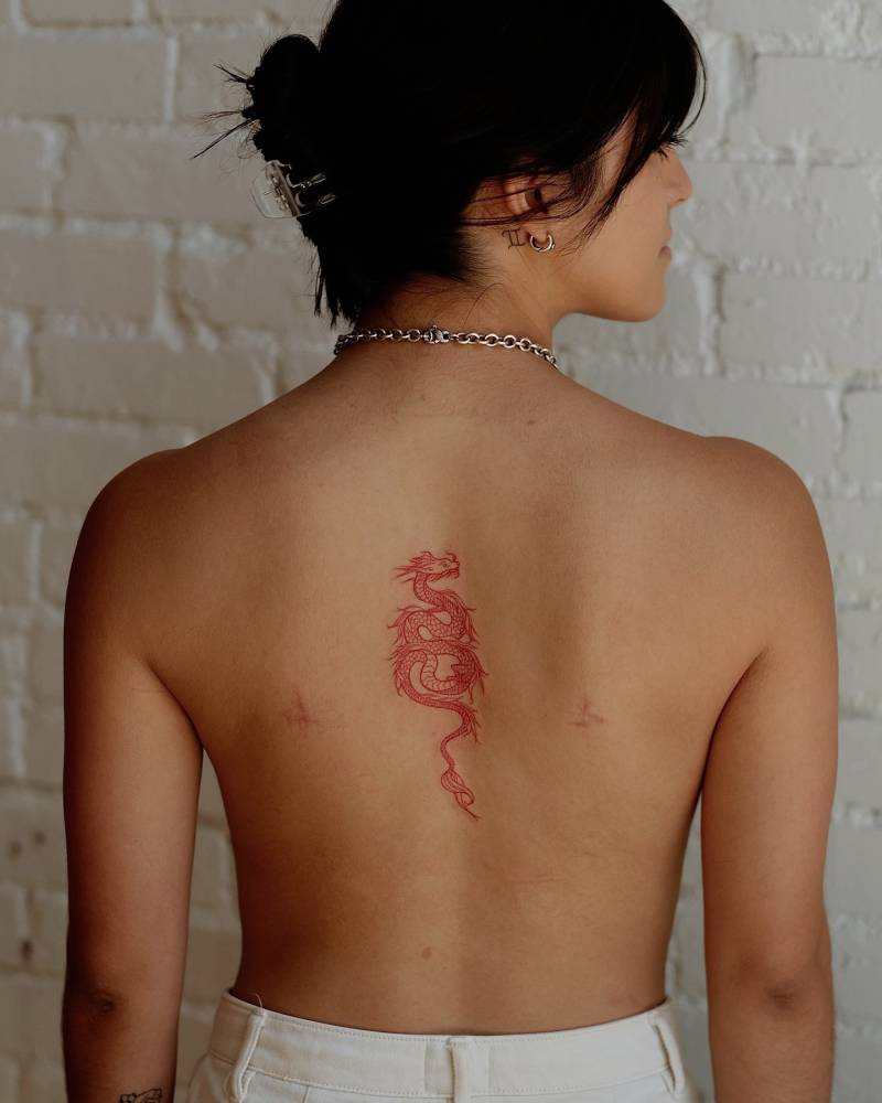Red dragon tattoo in fine line style located on the back.