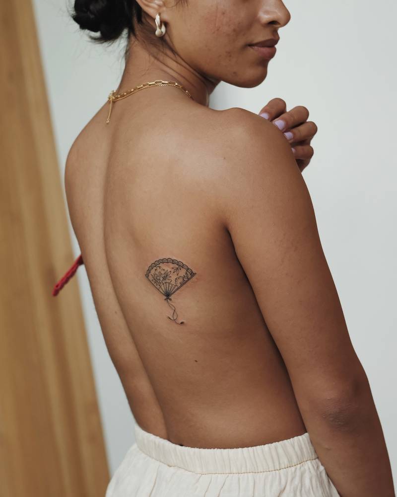 Illustrative style hand fan tattoo located on the shoulder blade.