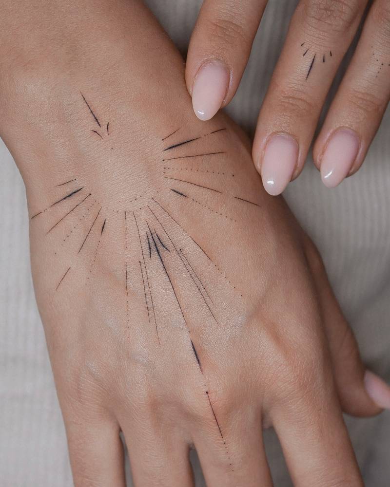 Fine line style ornamental sun tattoo located on the hand.