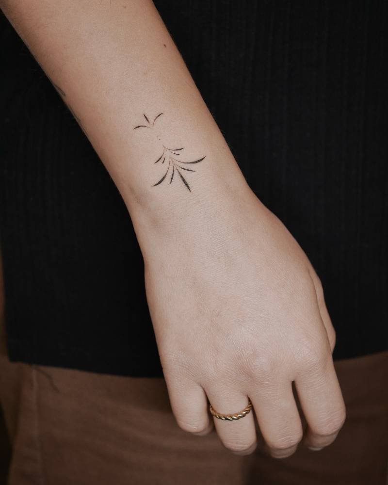 Line art style ornamental tattoo located on the wrist.