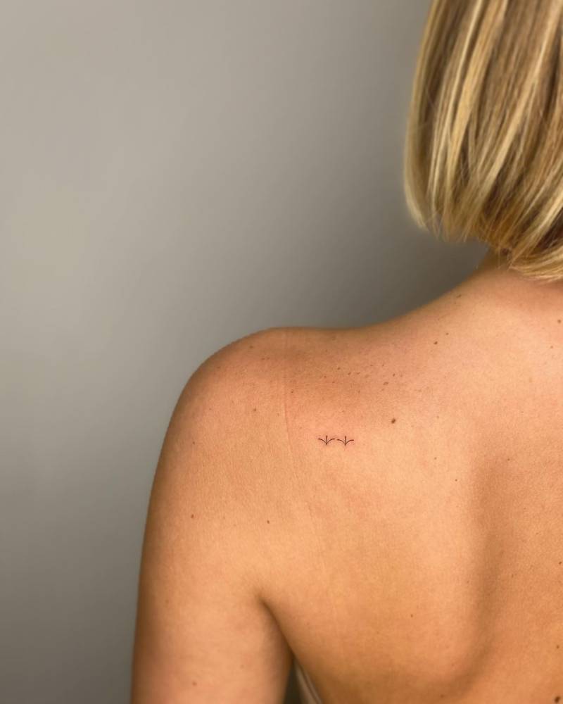 Minimalistic style ornament tattooed on the shoulder blade.