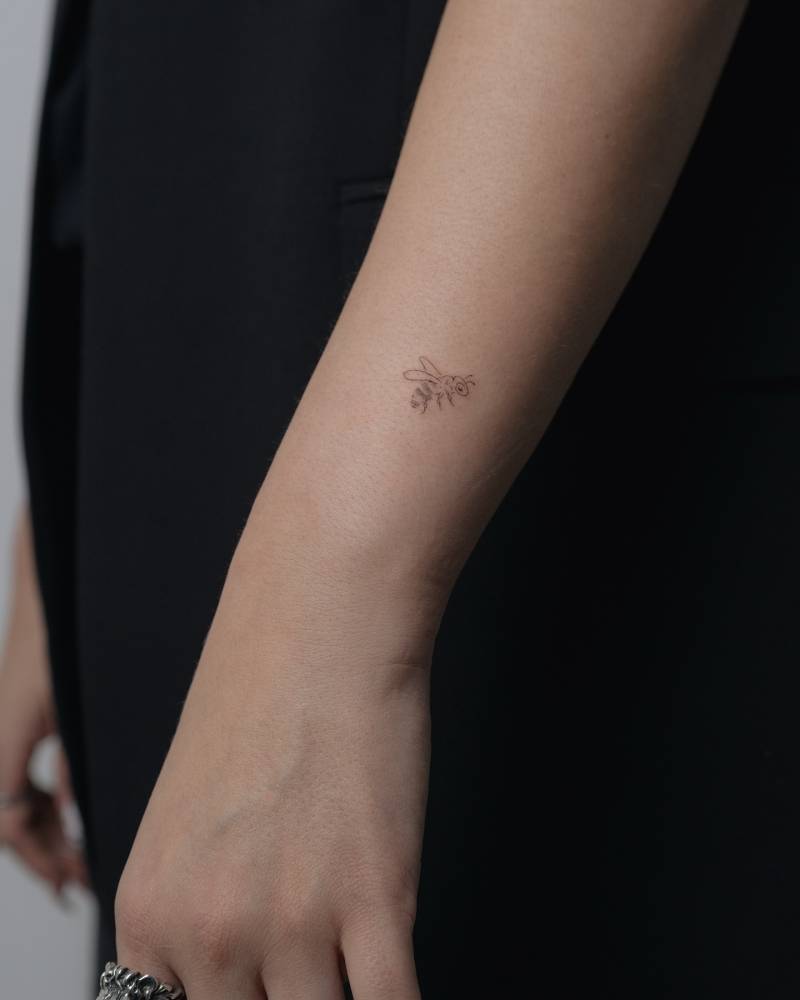 Single needle bee tattoo located on the wrist.