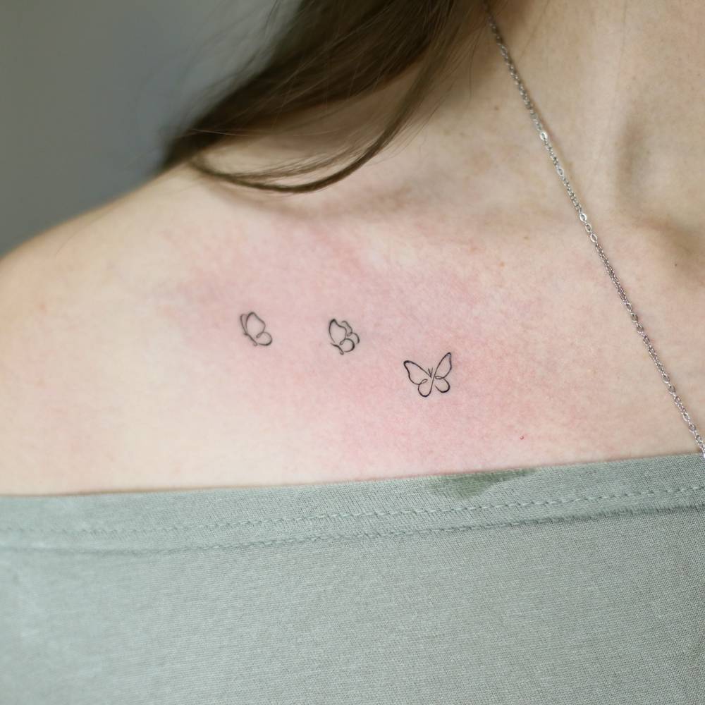Minimalistic style butterfly trio tattooed on the collarbone.