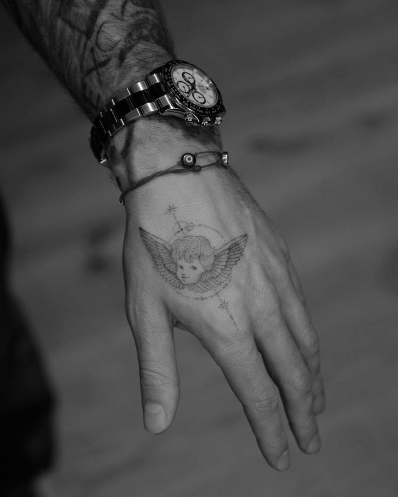 Single needle cherub tattoo located on the hand.