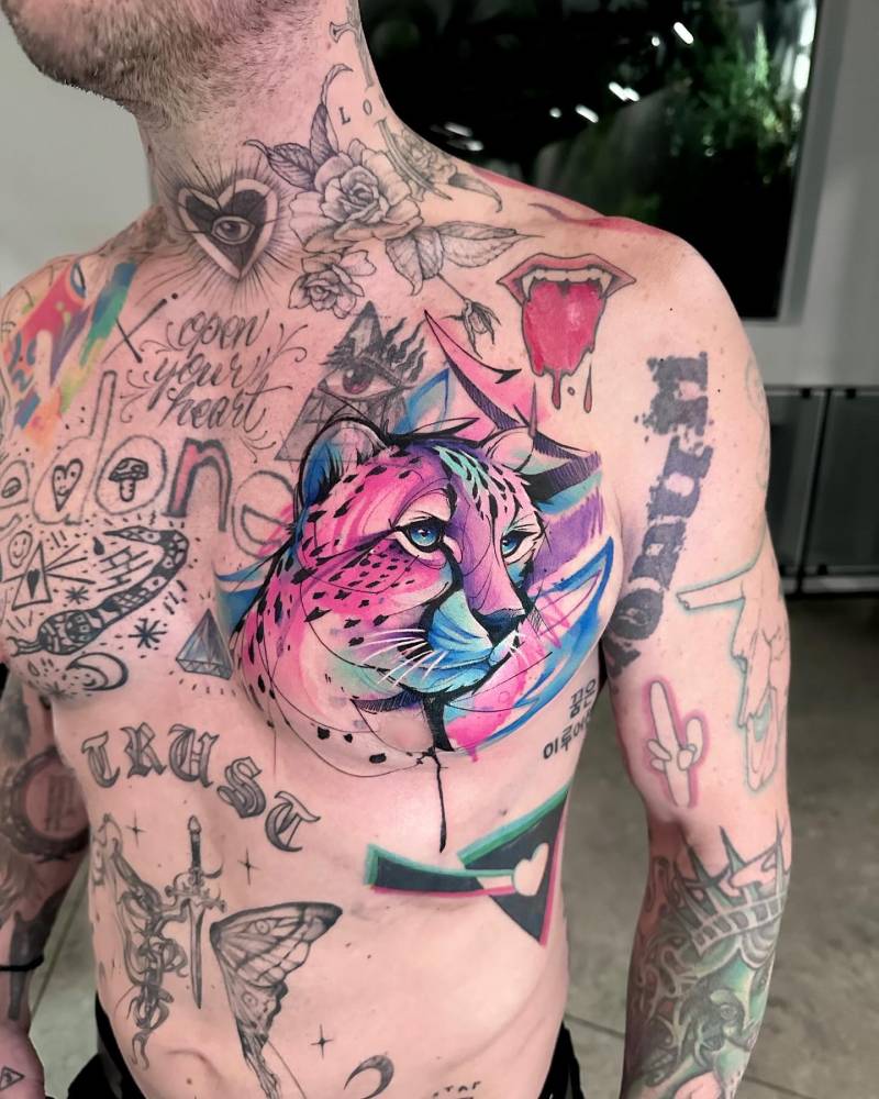 Watercolor style cheetah portrait tattoo located on the chest.