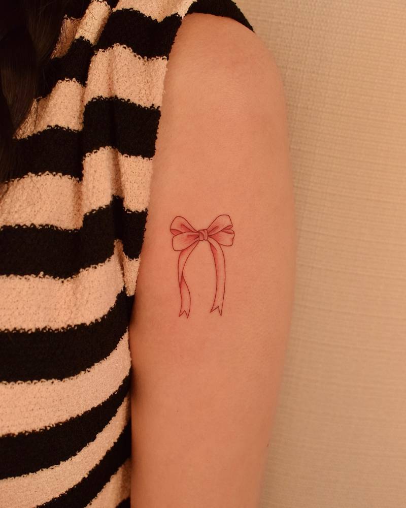 Illustrative style bow tattoo located on the upper arm.