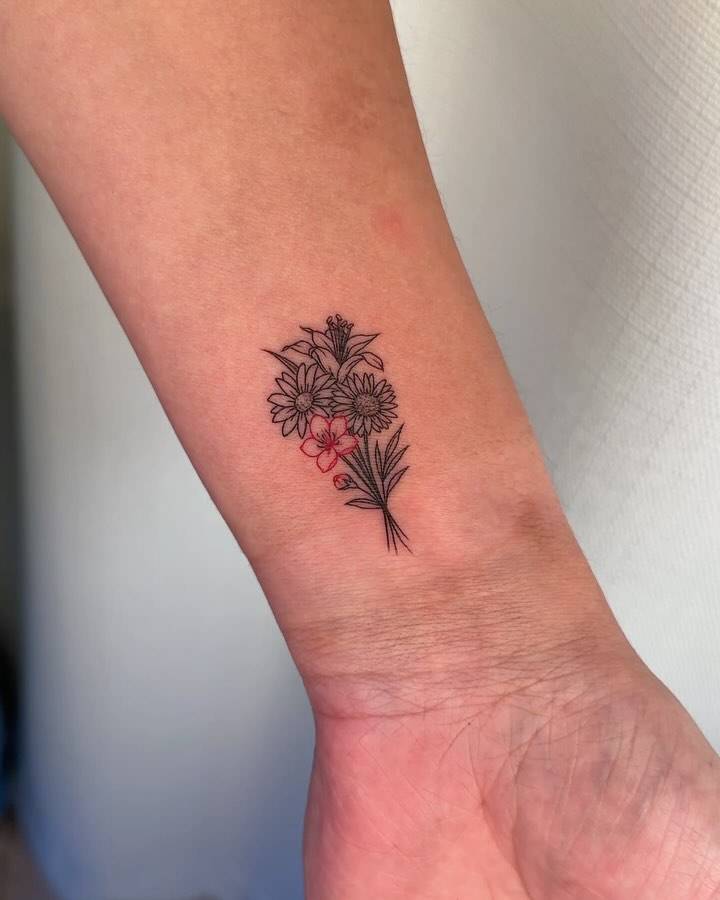 Fine line style flower bouquet tattoo located on the wrist.