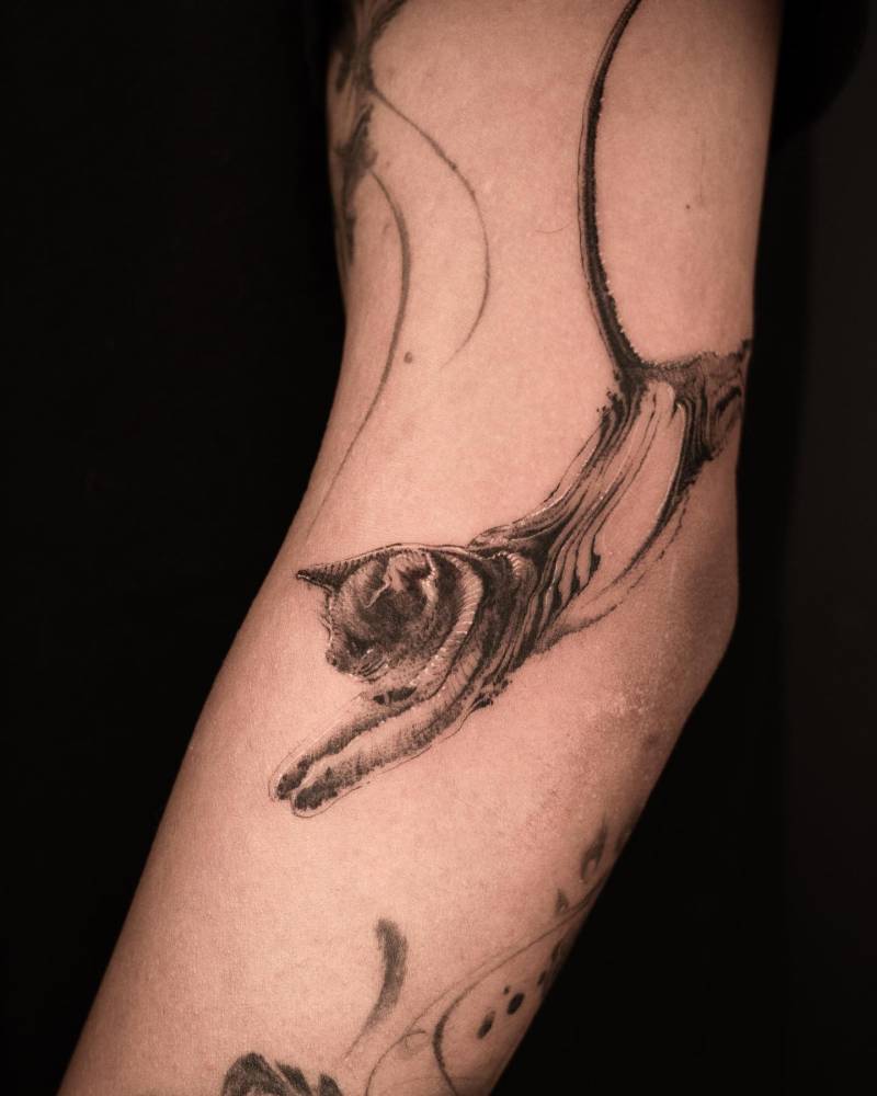 Blackwork style cat tattoo located on the elbow.