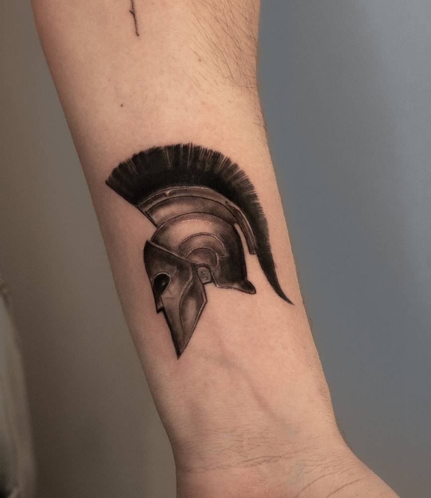 Micro-realistic style spartan helmet tattoo located on the wrist.