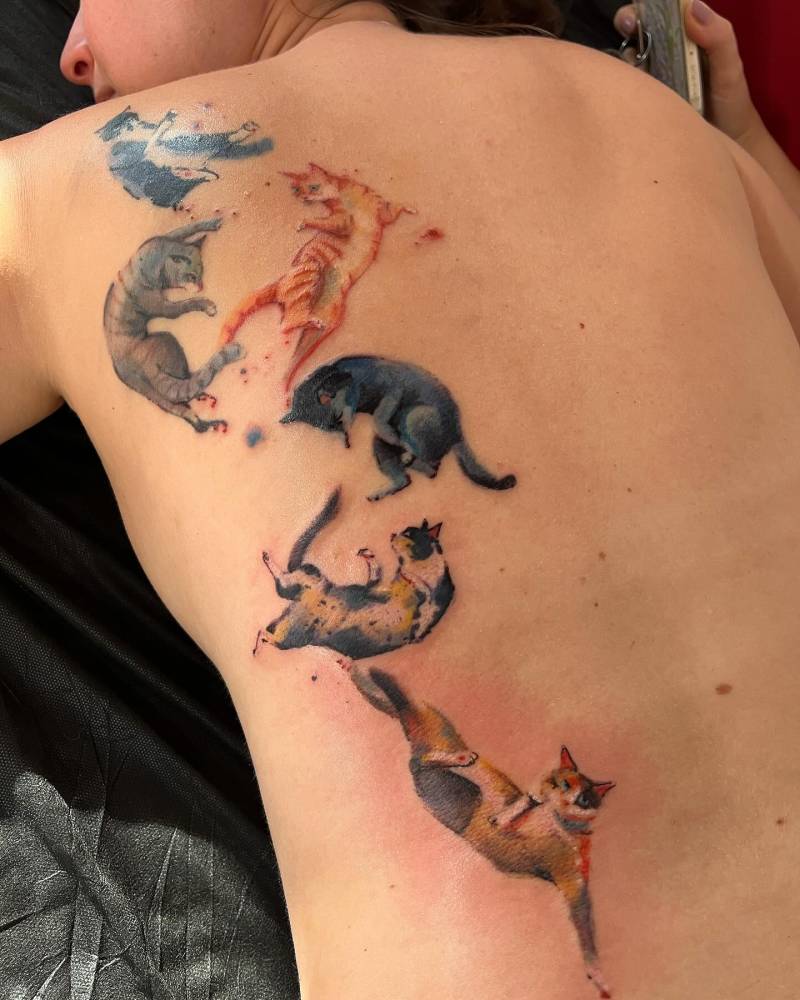 Cat collection tattoo located on the back, done in watercolor style.