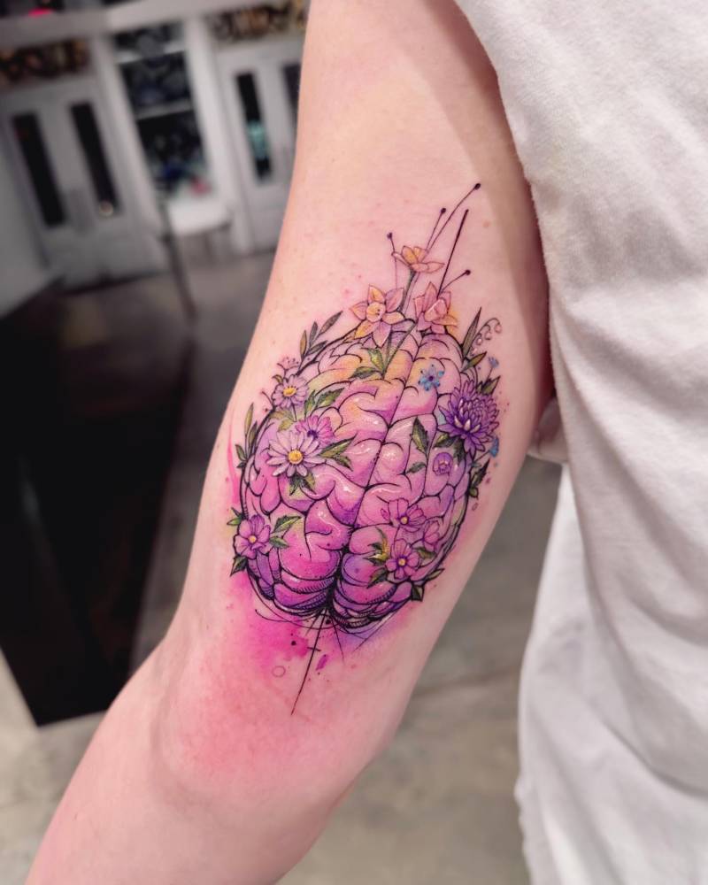 Brain and flowers tattooed on the tricep, done in watercolor style.