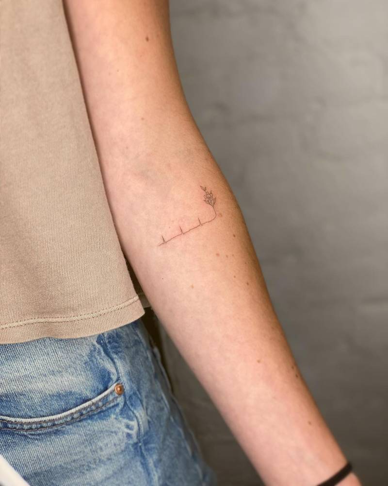 Fine line style heartbeat and flower tattoo located on the inner forearm.