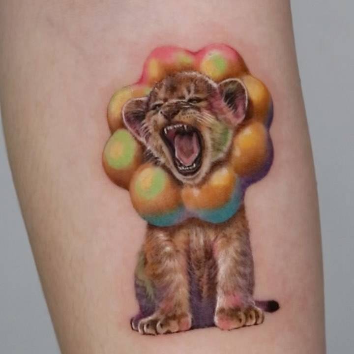 Micro-realistic style lion cub tattoo located on the inner forearm.