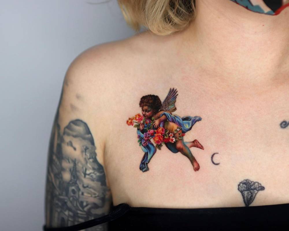 Realistic style cherub tattoo located on the chest.