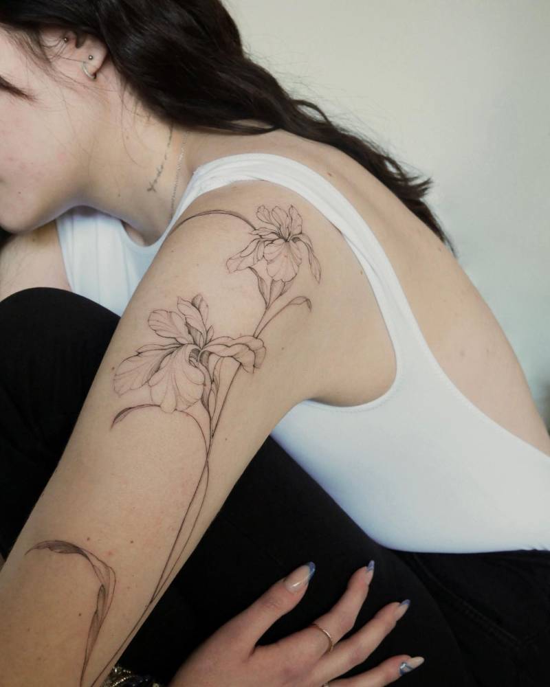 Iris flower tattoo located on the upper arm, done in illustrative style.