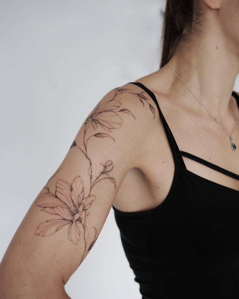 Magnolias tattoo located on the upper arm, illustrative style.