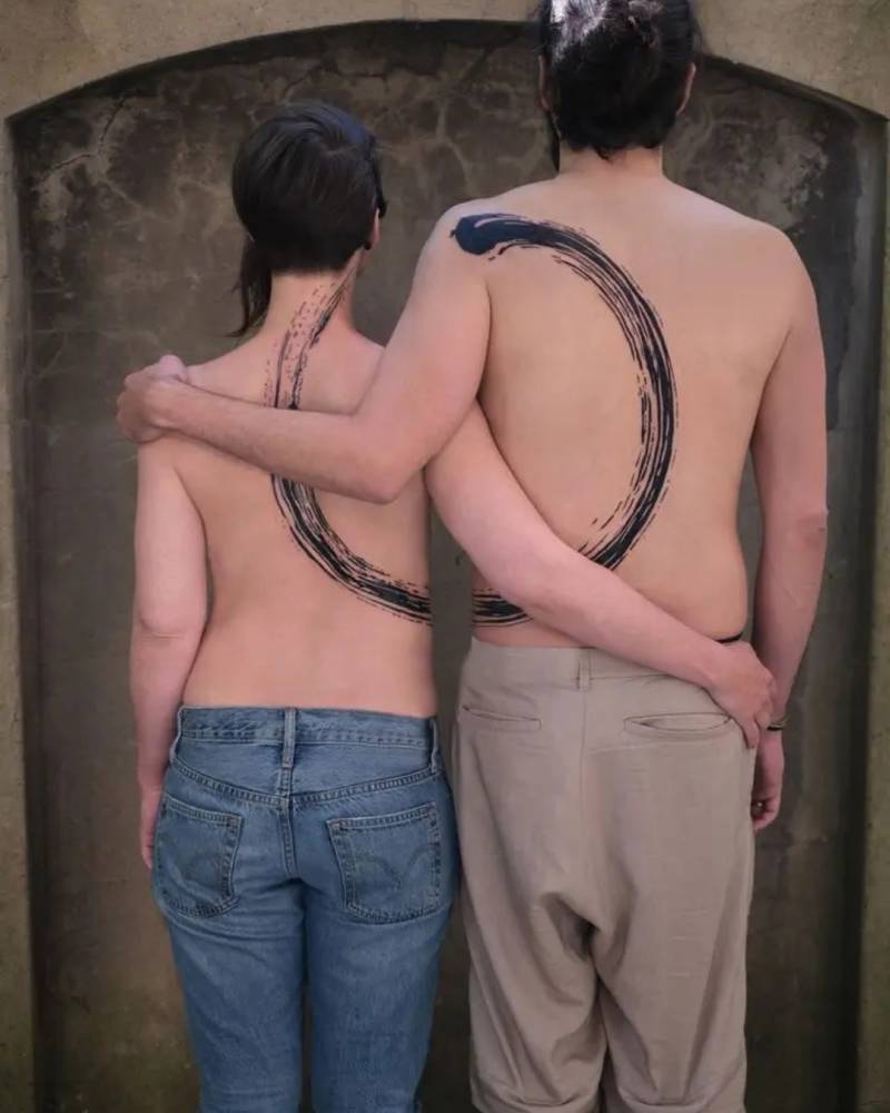 Couple's matching enso tattoo located on their backs.