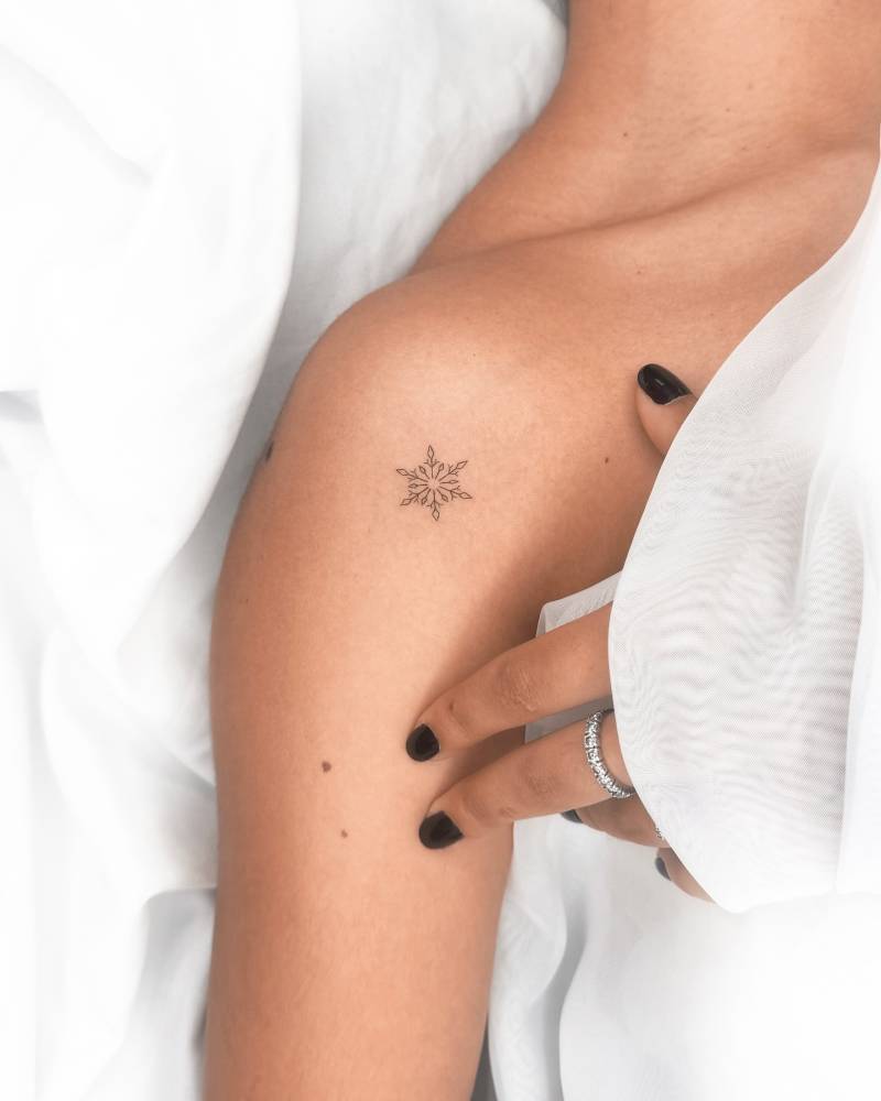 Snowflake tattoo in fine line style done on the shoulder.