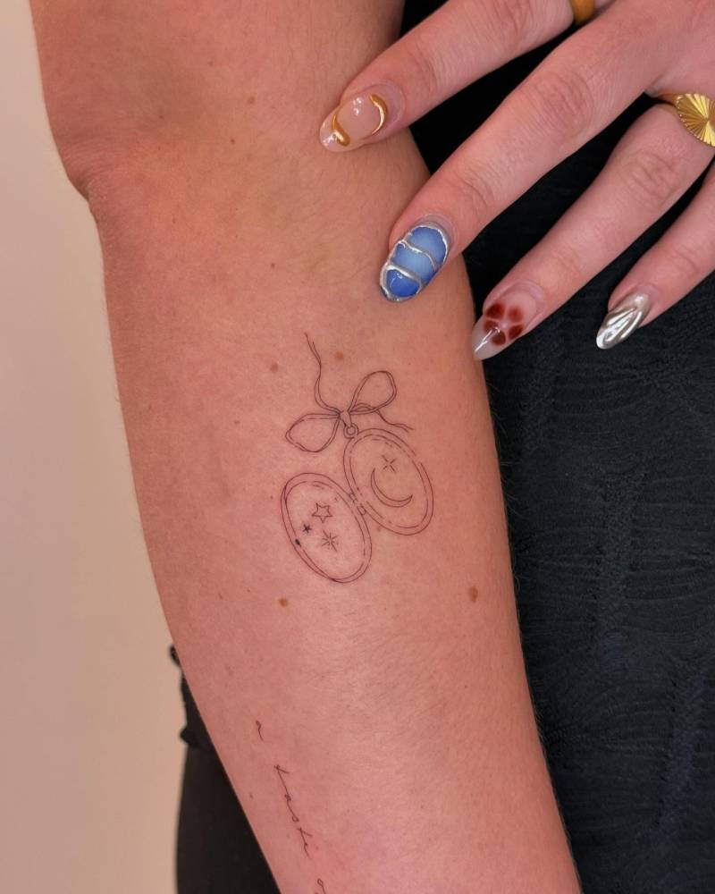 Fine line style pendant tattoo located on the forearm.