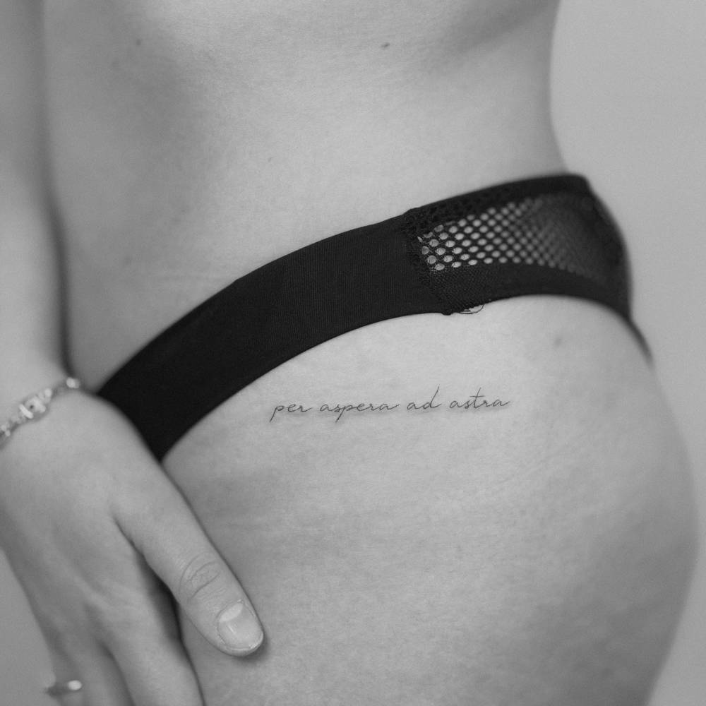 "Per aspera ad astra" handwritten lettering tattoo placed on the hip.