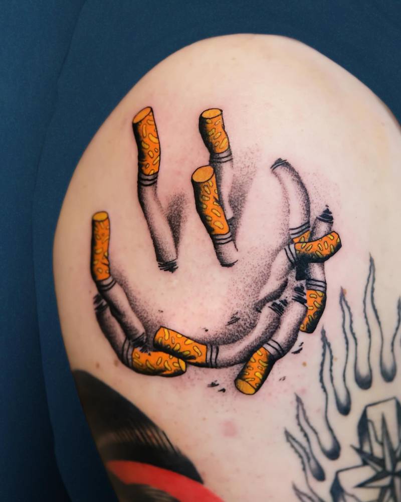 Cigarette smiley face tattoo located on the upper arm.