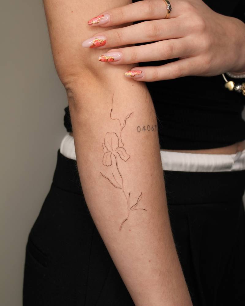 Sketch work style iris flower tattoo located on the forearm.