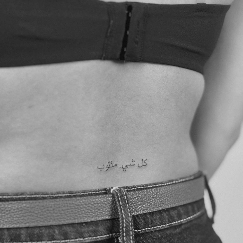 Arabic lettering tattoo located on the lower back.