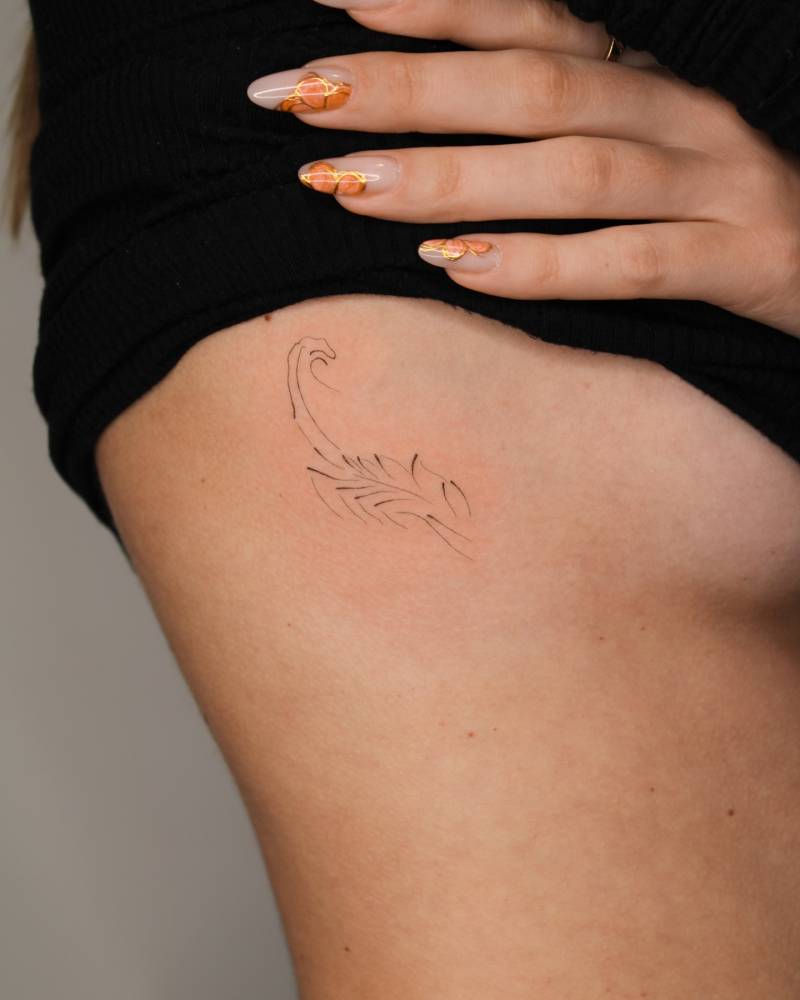 Abstract style scorpion tattoo located on the side boob.
