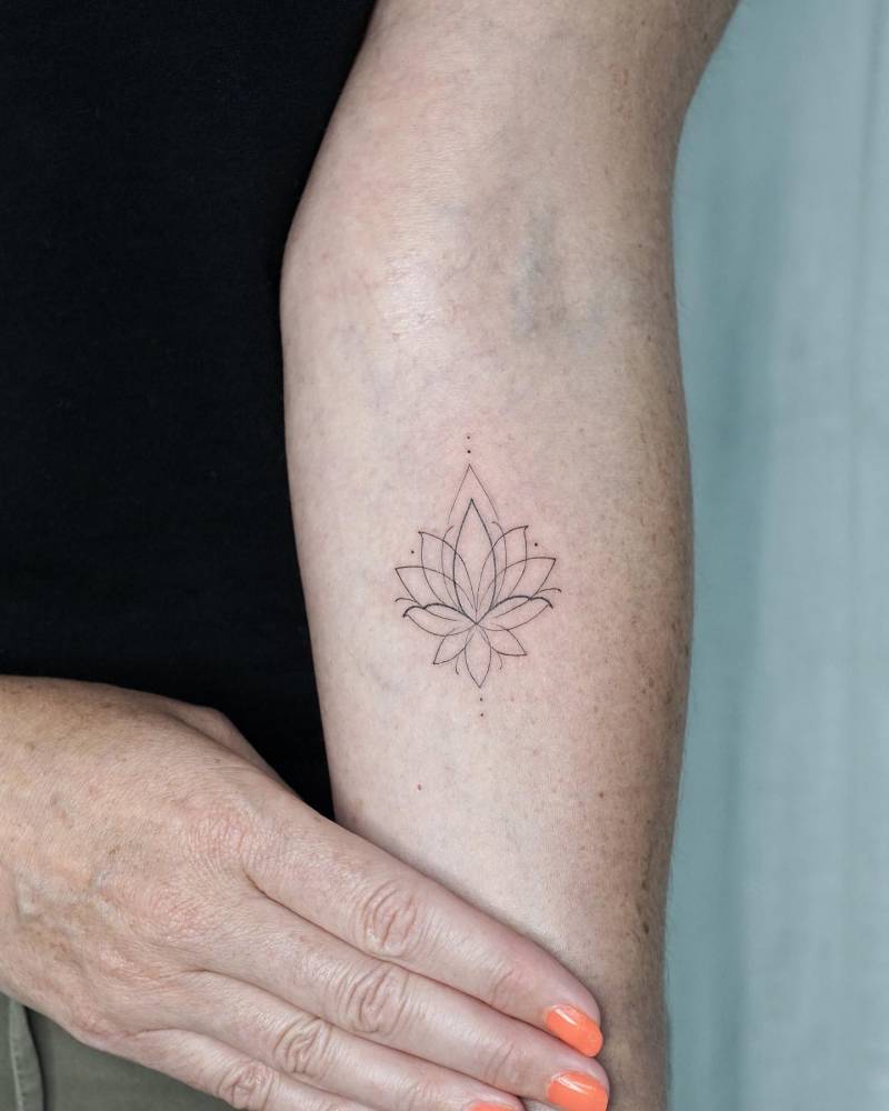 Little fine line lotus flower tattoo located on the inner forearm.