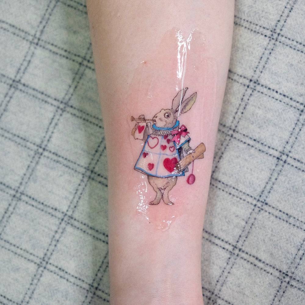 Cartoon style White Rabbit tattoo located on the inner forearm.