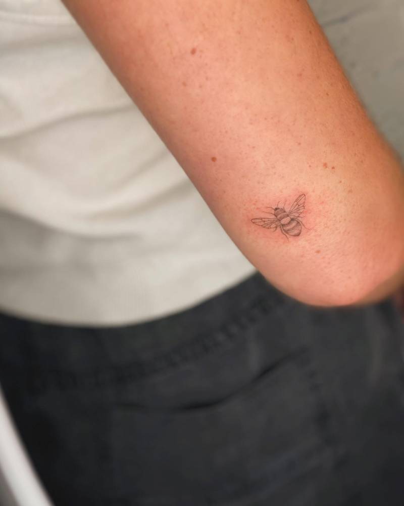 Fine line style bee tattoo done on the tricep.