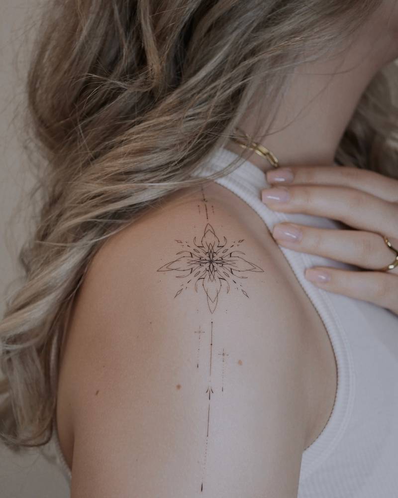 Fine line style ornamental tattoo located on the shoulder.