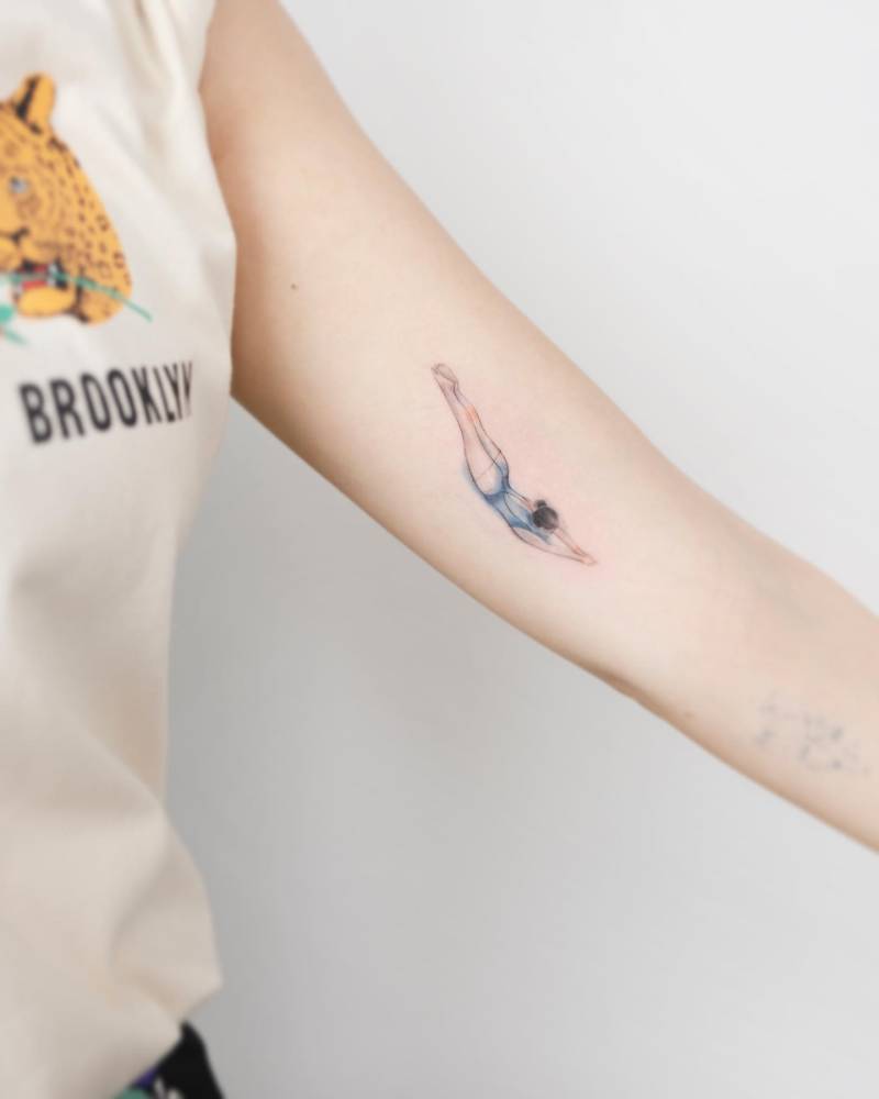 Watercolor style high diving tattoo located on the inner arm.