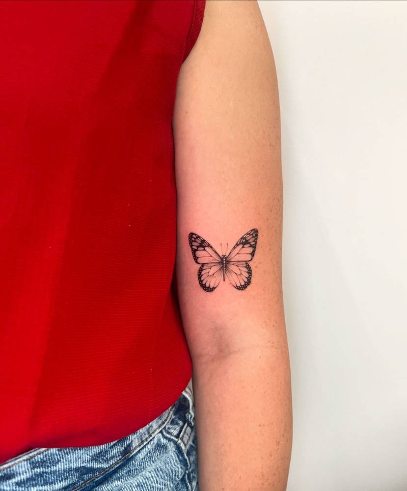 Illustrative style butterfly tattoo located on the bicep.