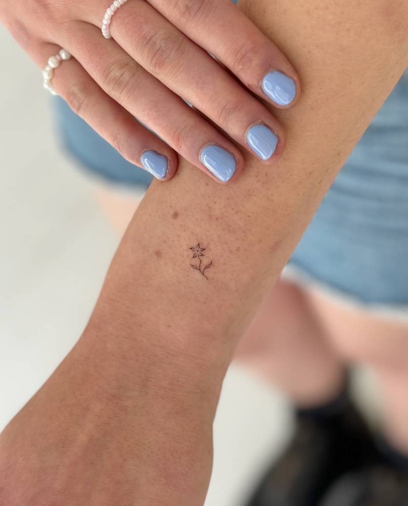 Tiny minimalistic flower tattoo located on the wrist.