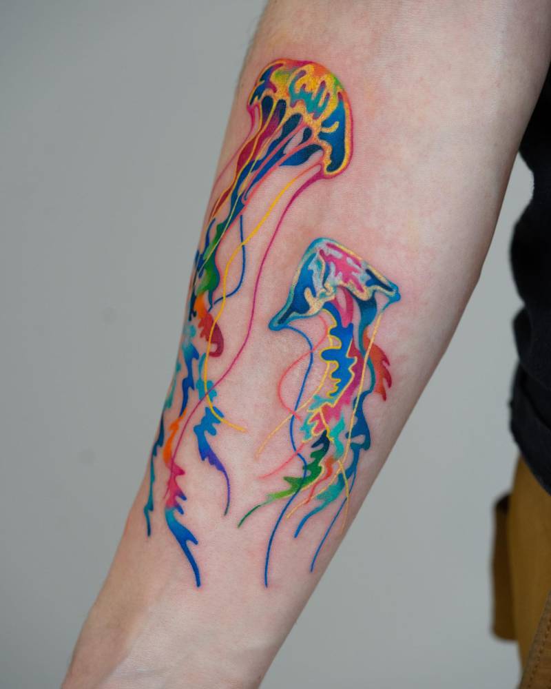 Watercolor style jellyfish tattoo located on the inner forearm.