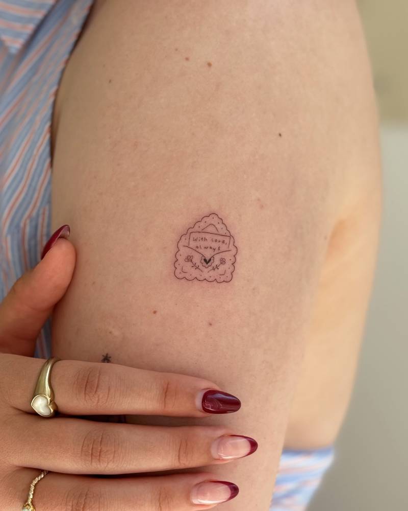 Fine line style love letter tattoo located on the upper arm.