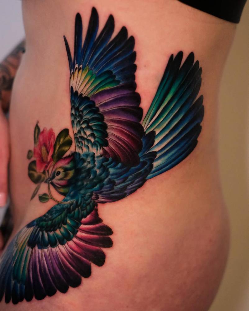 Illustrative style blue jay bird tattoo located on the side.