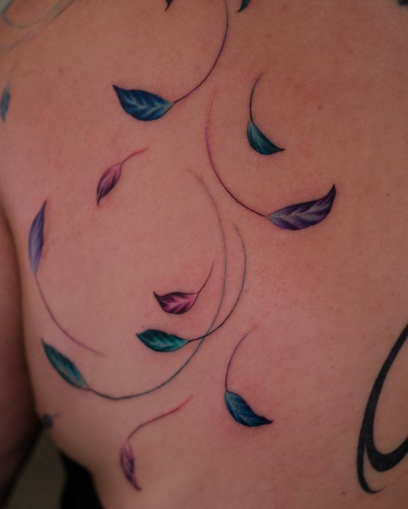 Watercolor style leaves tattoo located on the shoulder blade.