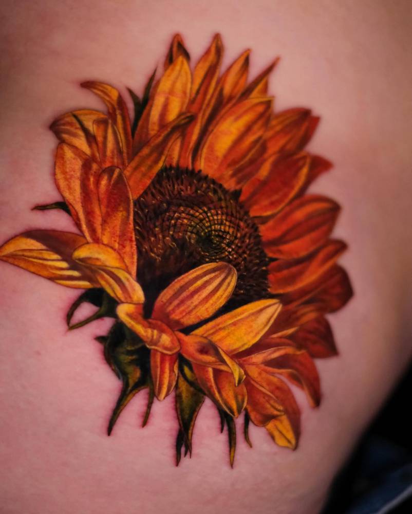 Realistic style sunflower tattoo located on the waist.