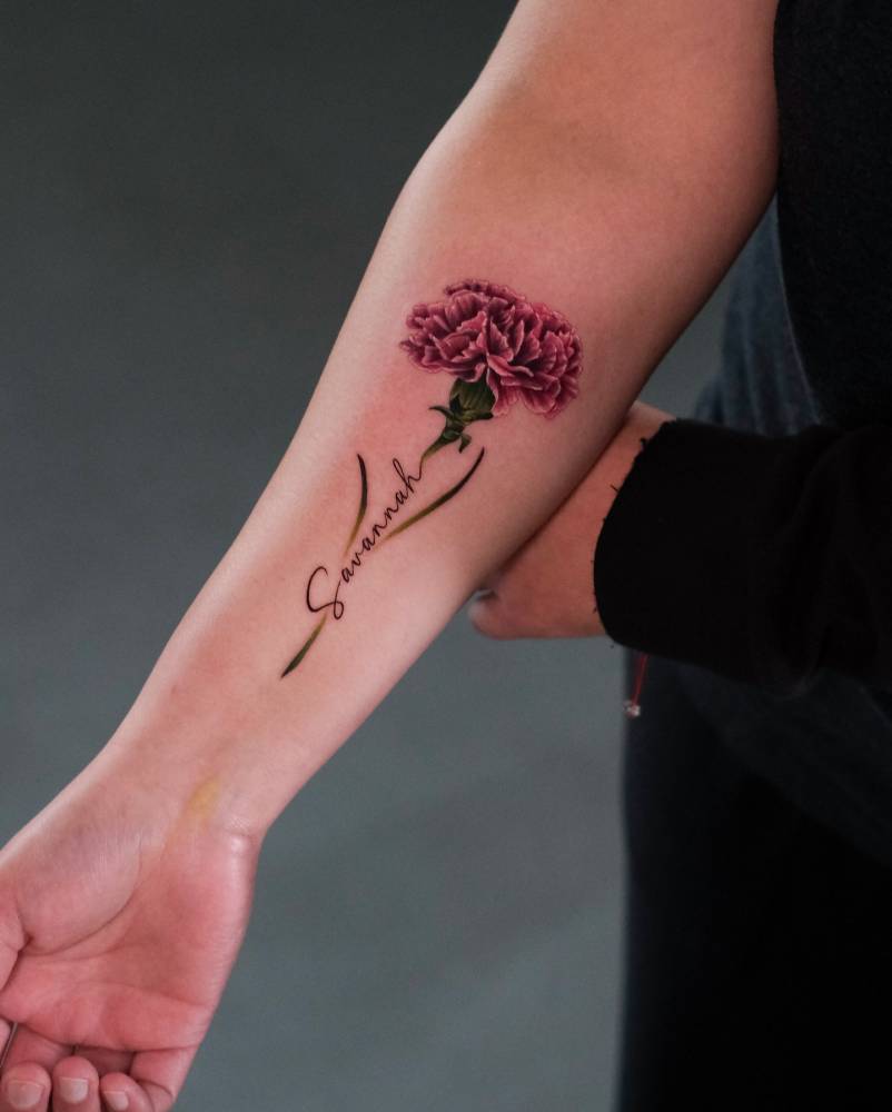 Carnation and name "Savannah" tattooed on the inner forearm.