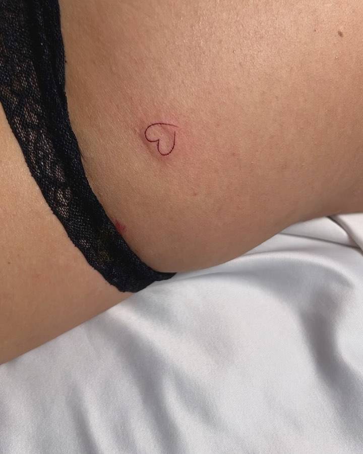 Minimalistic style heart tattoo located on the hip.