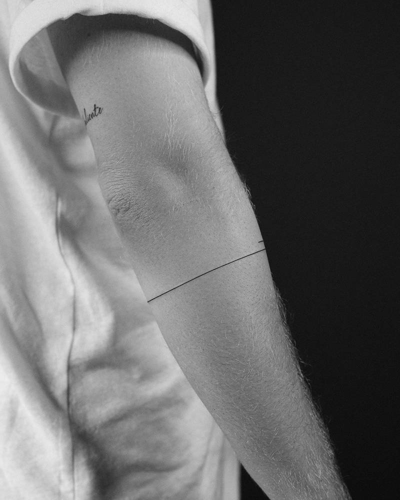Minimalistic style line bracelet tattoo located on the forearm.