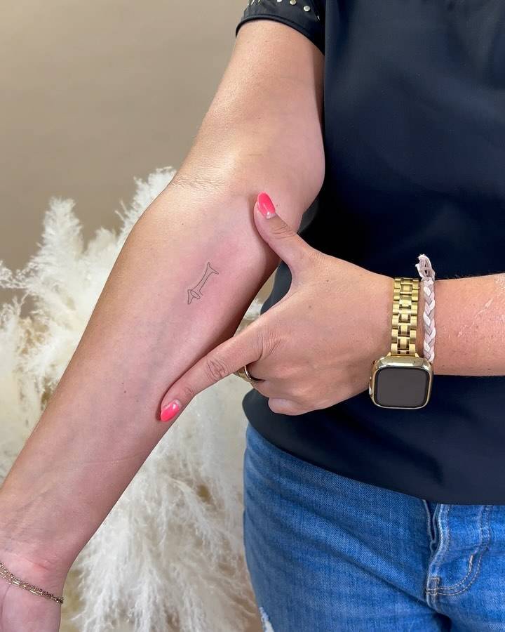 Fine line style 'Le Chien' tattoo located on the inner forearm.