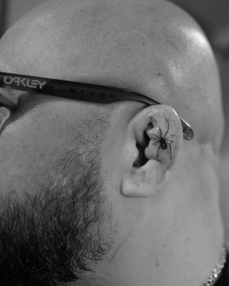 Single needle spider tattoo located on the ear.