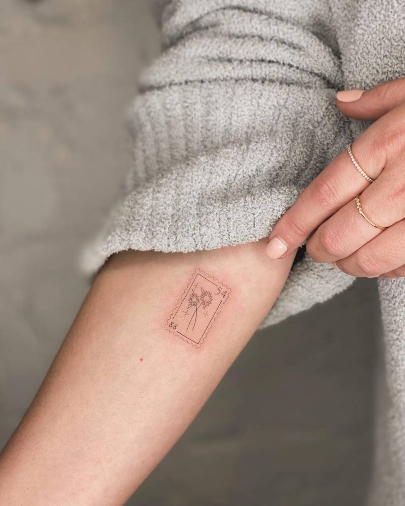 Fine line style sunflower stamp tattoo located on the inner forearm.