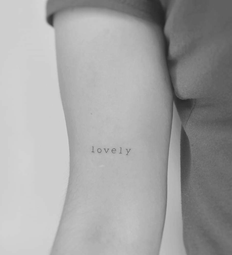 Lettering tattoo of the word "lovely" in typewriter font.